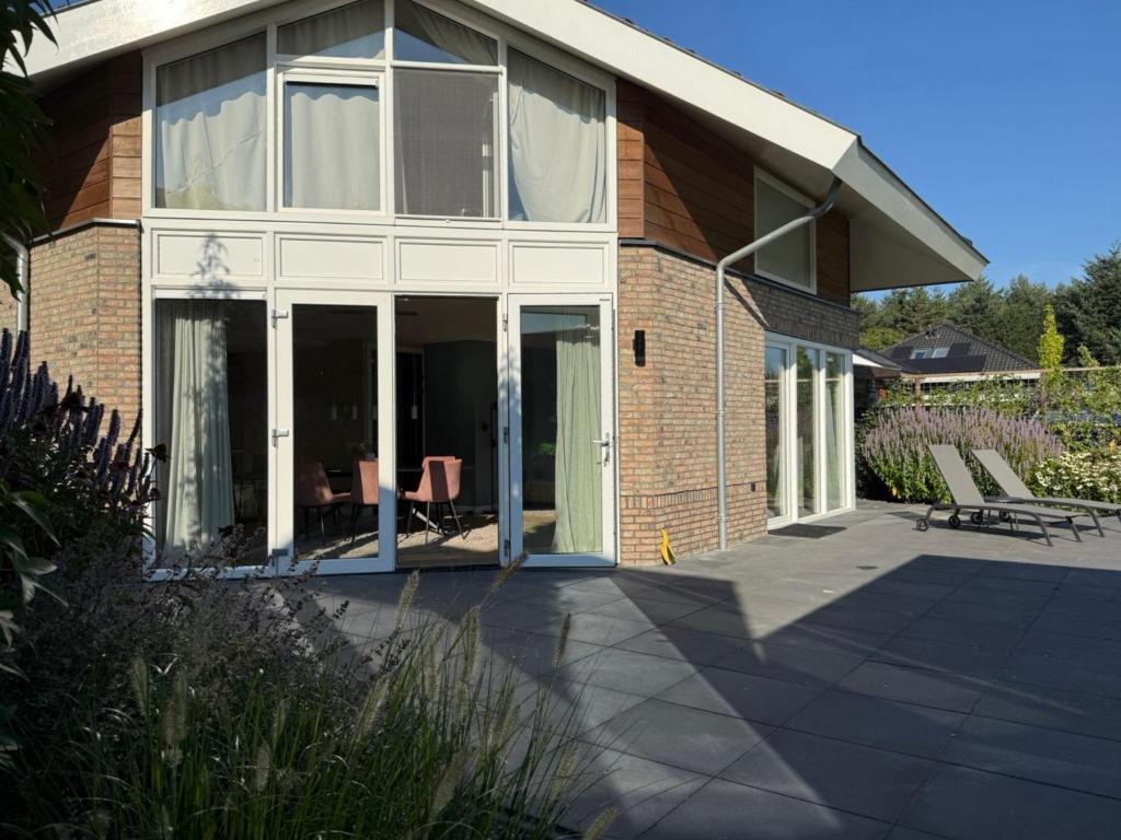 a house with glass doors and a patio at Wellness Escape with Private Sauna in Sibculo