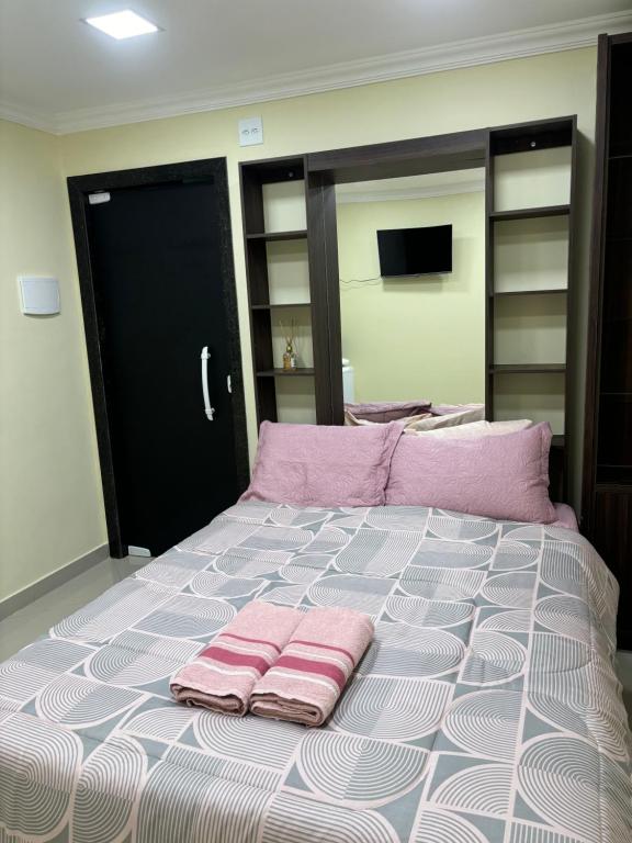 a bedroom with a large bed with pink pillows on it at Suíte sossego in Rio das Ostras