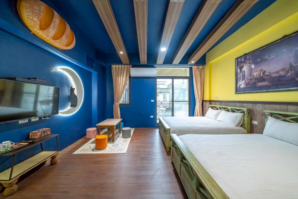 a blue room with two beds and a tv at 精彩奇寓站前電梯主題民宿走路到車站好停車 in Hualien City