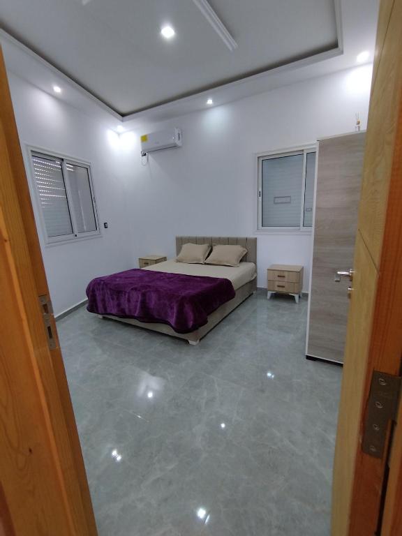 a bedroom with a bed with a purple blanket at Djerba Haven Family in Houmt Souk