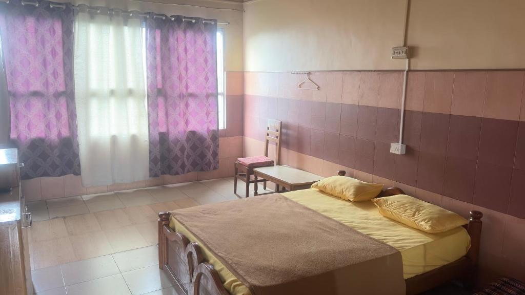 a bedroom with a bed and a table and a window at Vega tourist lodge in Madikeri