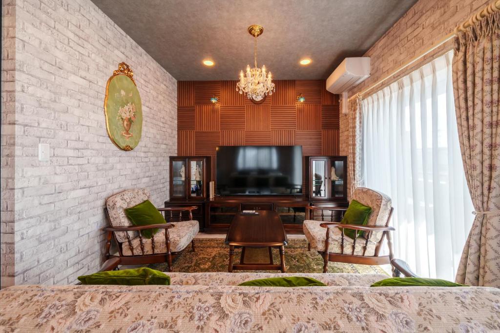 a living room with a tv and a couch and chairs at ルグランみしま Private lodging in Hamamatsu
