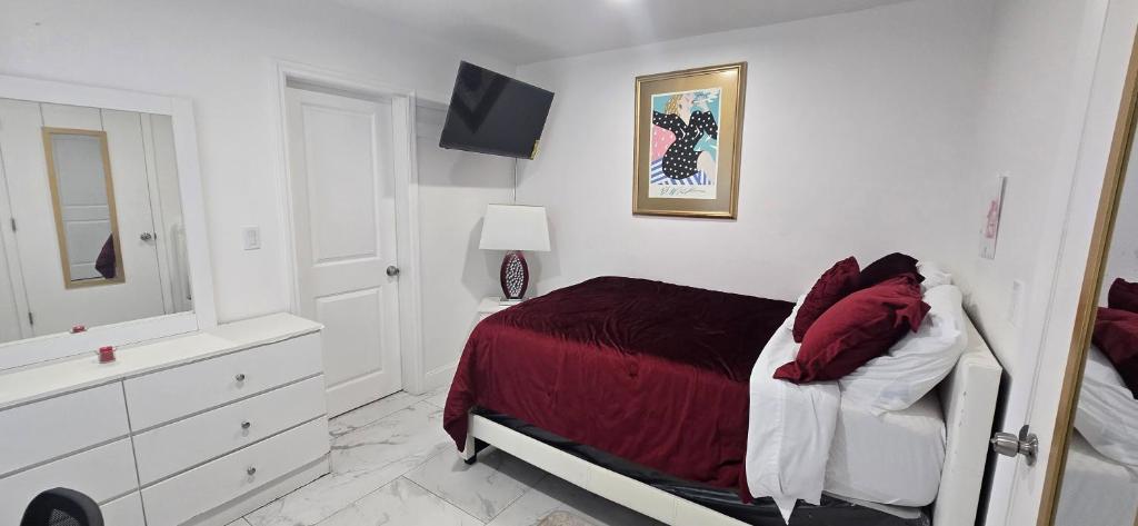 a white bedroom with a bed with a red blanket at Araly's house in Tampa