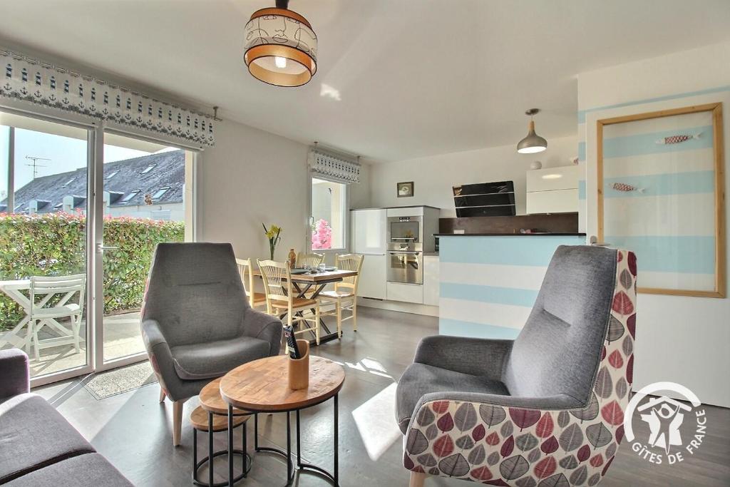 a living room with chairs and a table and a kitchen at Le randonneur in Pleubian