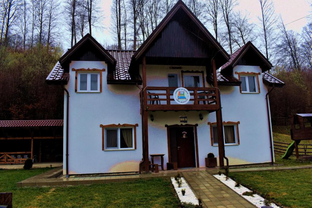a small white house with a black roof at Casa Vanatorului Buzaiel in Vama Buzăului