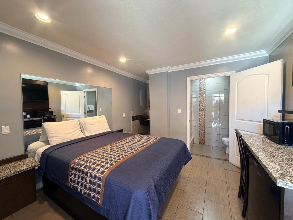 a bedroom with a large bed and a bathroom at Stallion Motel Los Angeles in Los Angeles