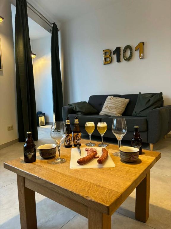 a wooden table with glasses of wine and sausages at Bivouac 101 in Bastogne