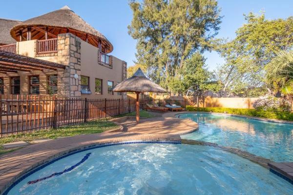 a swimming pool with an umbrella in front of a house at The palace in Sandton