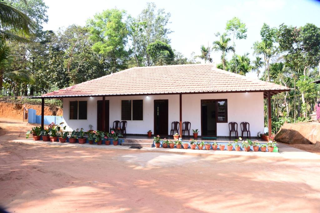 a small white house with a lot of flowers in front at BlueMoon Homestay - Near to Falls and View Points, Home Food & Estate in Sakleshpur