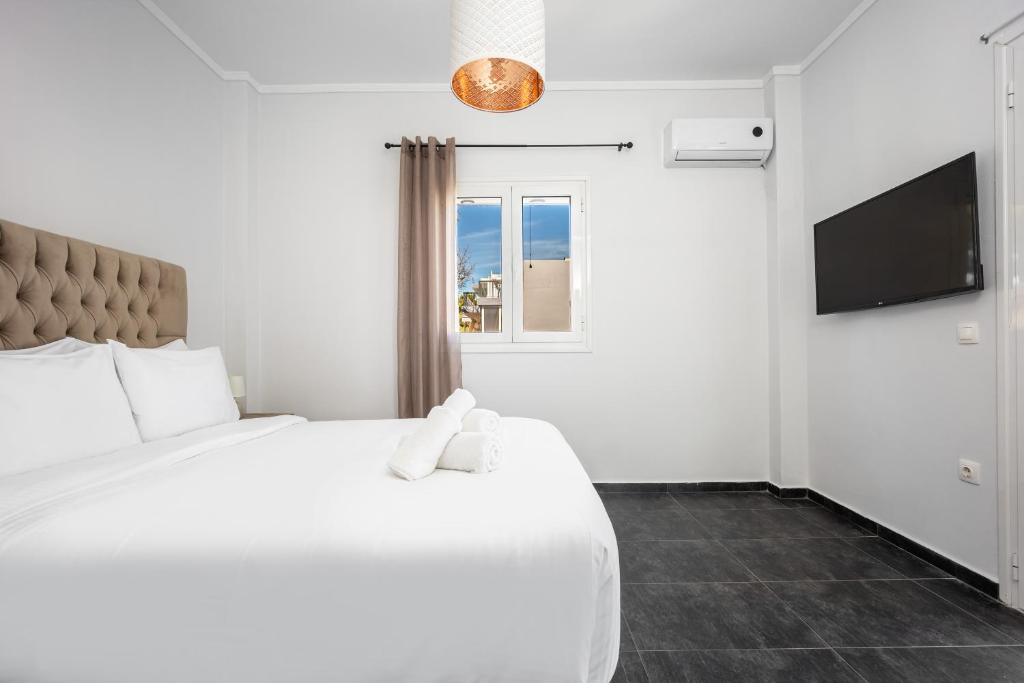 a white bedroom with a large bed and a window at Athenean Sea Breeze in Vari