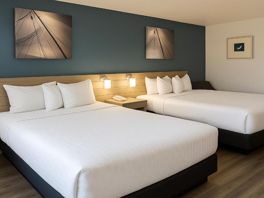 a hotel room with two beds with white sheets at Rancho San Diego Inn & Suites in El Cajon