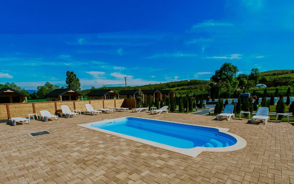 a swimming pool in a patio with chairs at Roben Village in Suseni