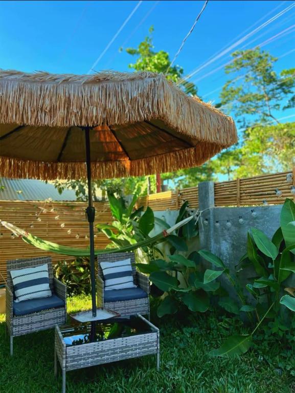 two chairs under a straw umbrella in the grass at Liminaya Villa in El Nido