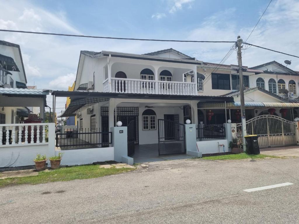 a white house with a balcony on a street at D' Saras Homestay in Sitiawan