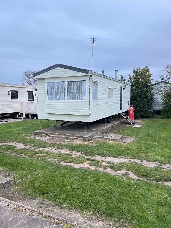 a white mobile home sitting in a yard at Seawick Beach Caravan in Saint Osyth
