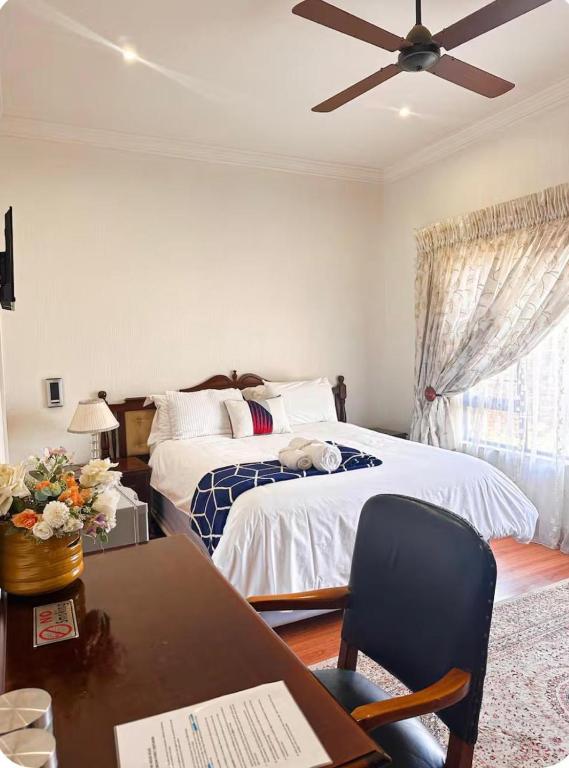 a bedroom with a bed and a desk with a chair at Tsheryl's Residence in Centurion