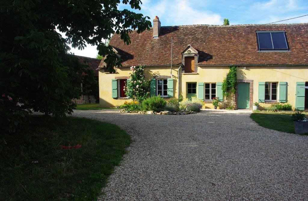 a large yellow house with a gravel driveway at Jardin Solstice in Vaupillon