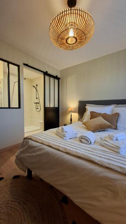 a bedroom with a large white bed with a chandelier at LUCIA AL MARE - chambre d'hôtes in Châtelaillon-Plage