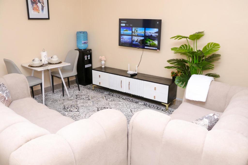 a living room with two white couches and a tv at Gee Homes and Stays in Nyahururu