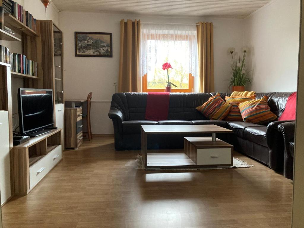 a living room with a black leather couch and a tv at Huber Hof in Oberrosenauerwald