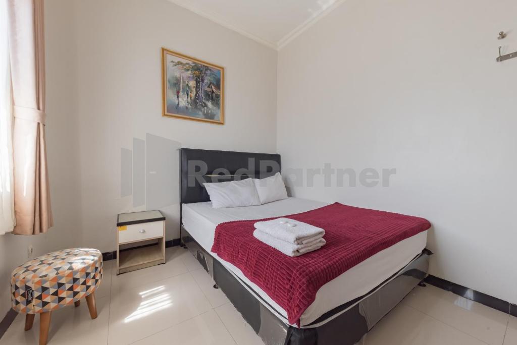 a small bedroom with a bed and a chair at Wisma Brata 2 Mitra RedDoorz in Nyomolong