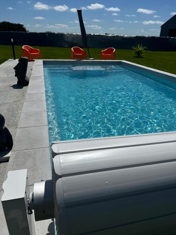 a swimming pool with chairs in a yard at La Maison De Parrain in Kerlouan