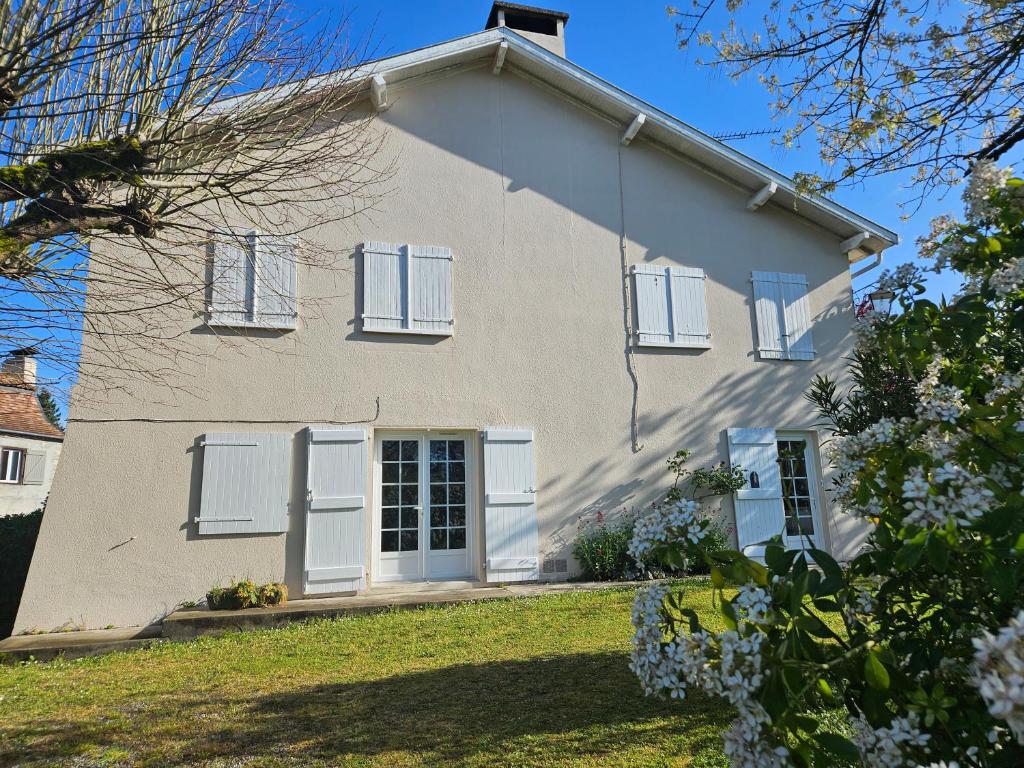 a white house with white shutters on it at Grande maison familiale avec jardin- 10 pers au coeur du Bearn in Guinarthe-Parenties