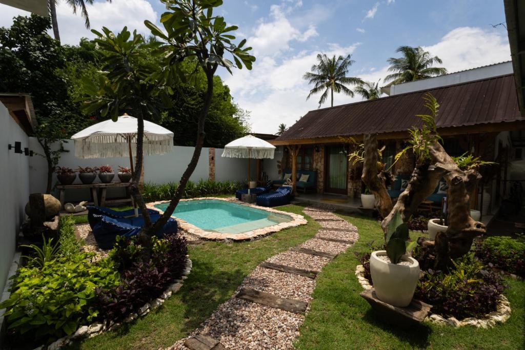 a backyard with a swimming pool and a house at The Swan Villa in Gili Trawangan