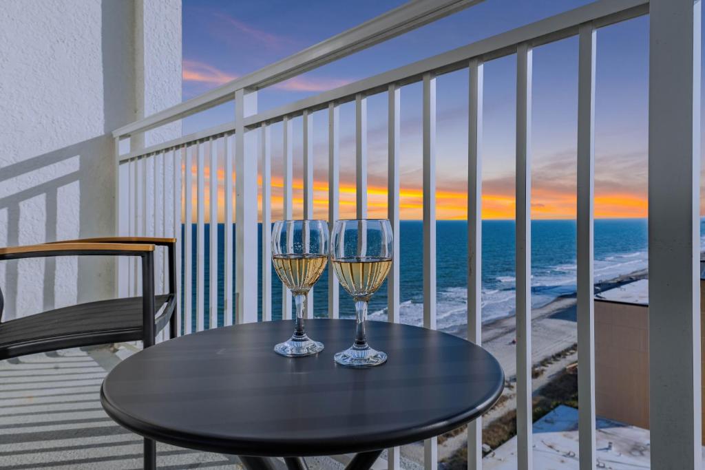 a table with two wine glasses on a balcony at Beach View Condo in Myrtle Beach