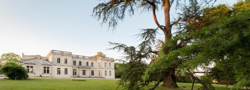 a large white house with a tree in the foreground at Hôtel Château La Chèze - Bordeaux Floirac in Floirac