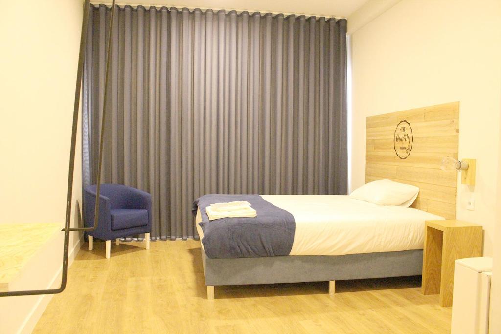 um quarto com uma cama e uma cadeira azul em HI!GO em Vila Nova de Famalicão