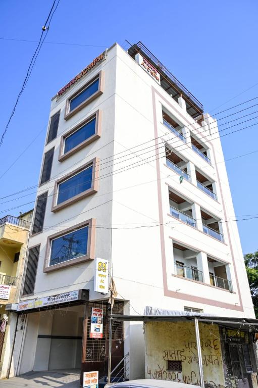 a white building with blue windows at Laxman AC Lodge Jejuri - by Martandbhairav hospitality LLP in Jejūri