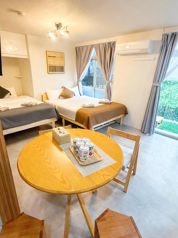 a hotel room with two beds and a table at Court Ada -1min to Araiyakushi-mae Station, 9min train to Shinjuku- 新井薬師前駅徒歩50秒 in Tokyo