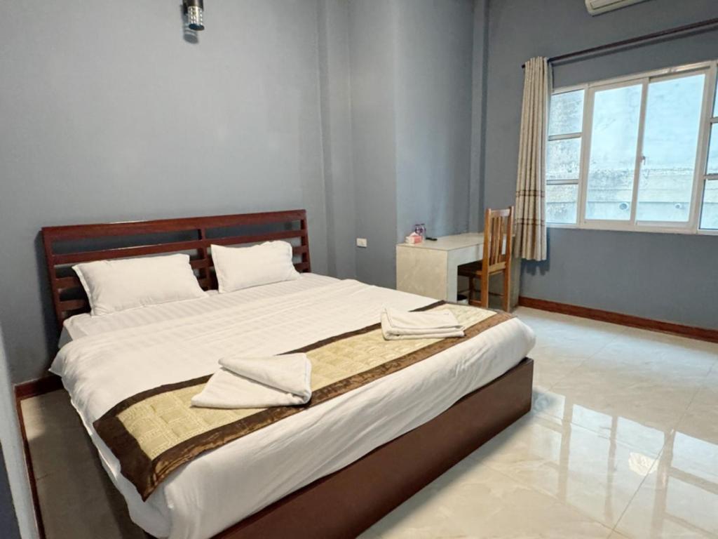 a bedroom with a large bed with white sheets and a window at Meesokxay Hotel Vang Vieng in Vang Vieng