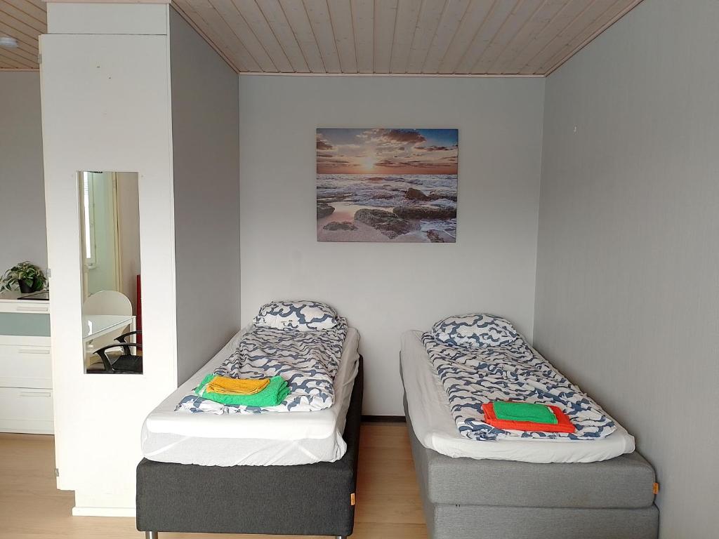 two twin beds in a room with a mirror at Flexible Myllykallio in Jyväskylä