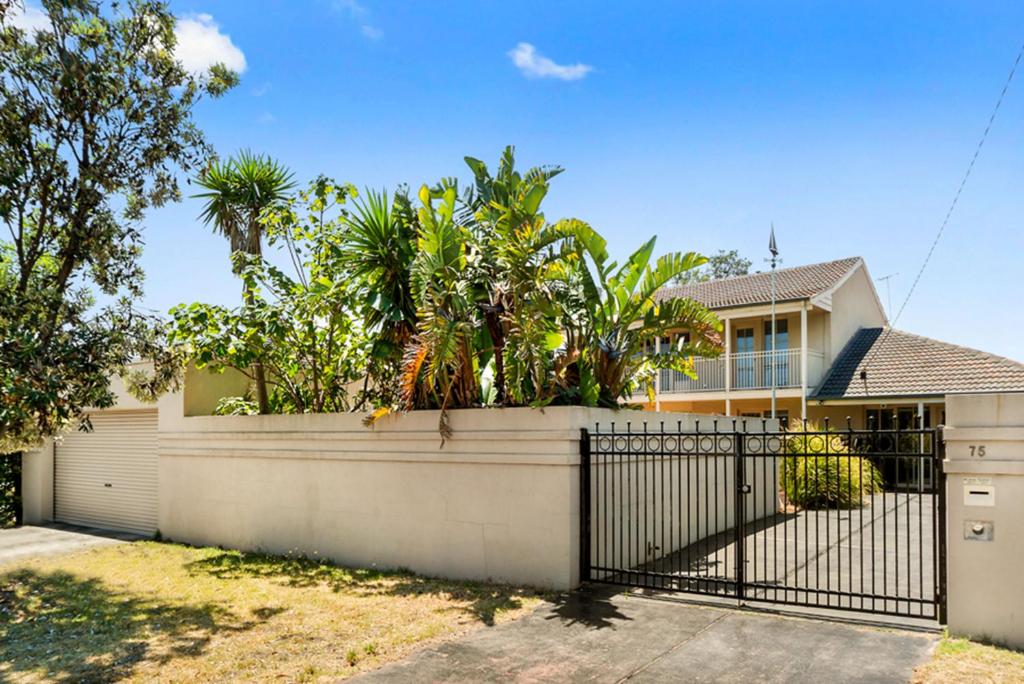 a house with a fence and trees in front of it at Isle of Serenity in Frankston