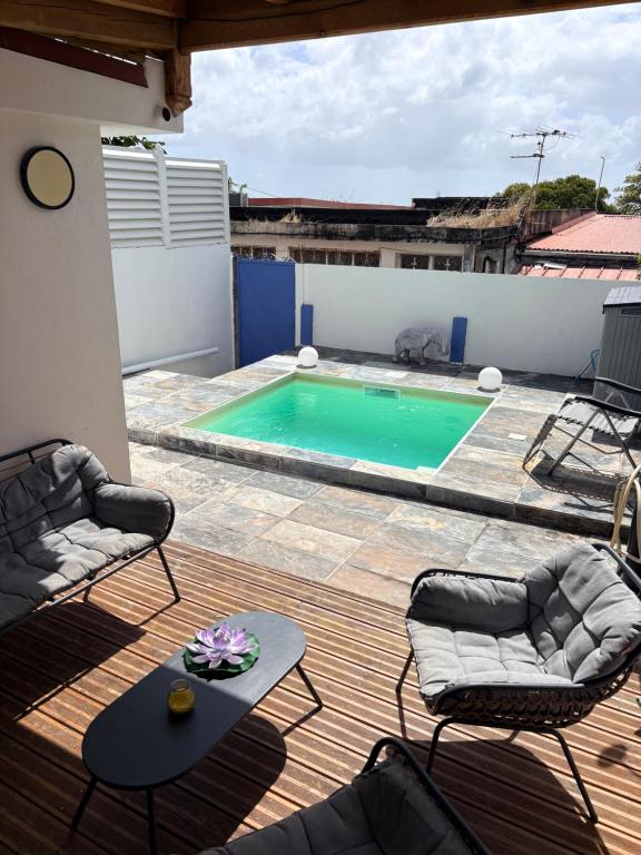 a swimming pool with two chairs and a table on a deck at Villa lyly blue in Case-Pilote
