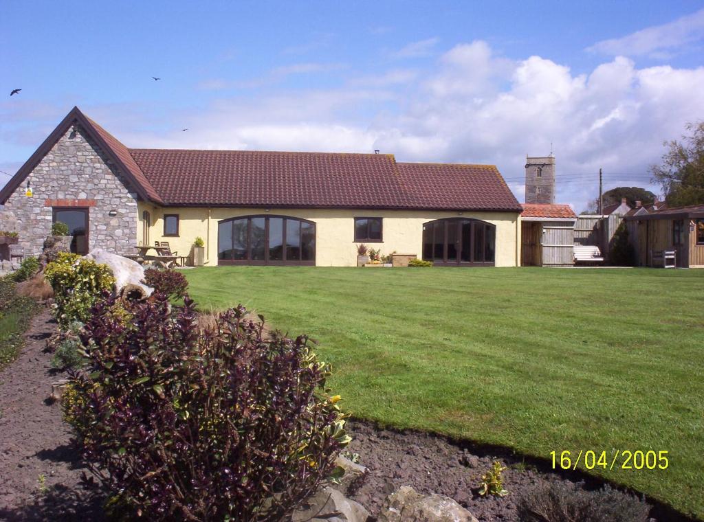 une maison avec une pelouse verte devant elle dans l'établissement WILLOW BARN boutique B&B, à Worle