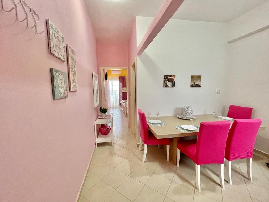 a dining room with pink walls and a table and chairs at FLY, Oneiropagida, Aegina in Vathí