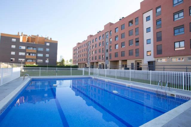 une grande piscine en face de certains bâtiments dans l'établissement Apartamento el Parque piscina aire acondicionado a 5 minutos del centro en coche entorno tranquilo ideal mascotas, à Logroño
