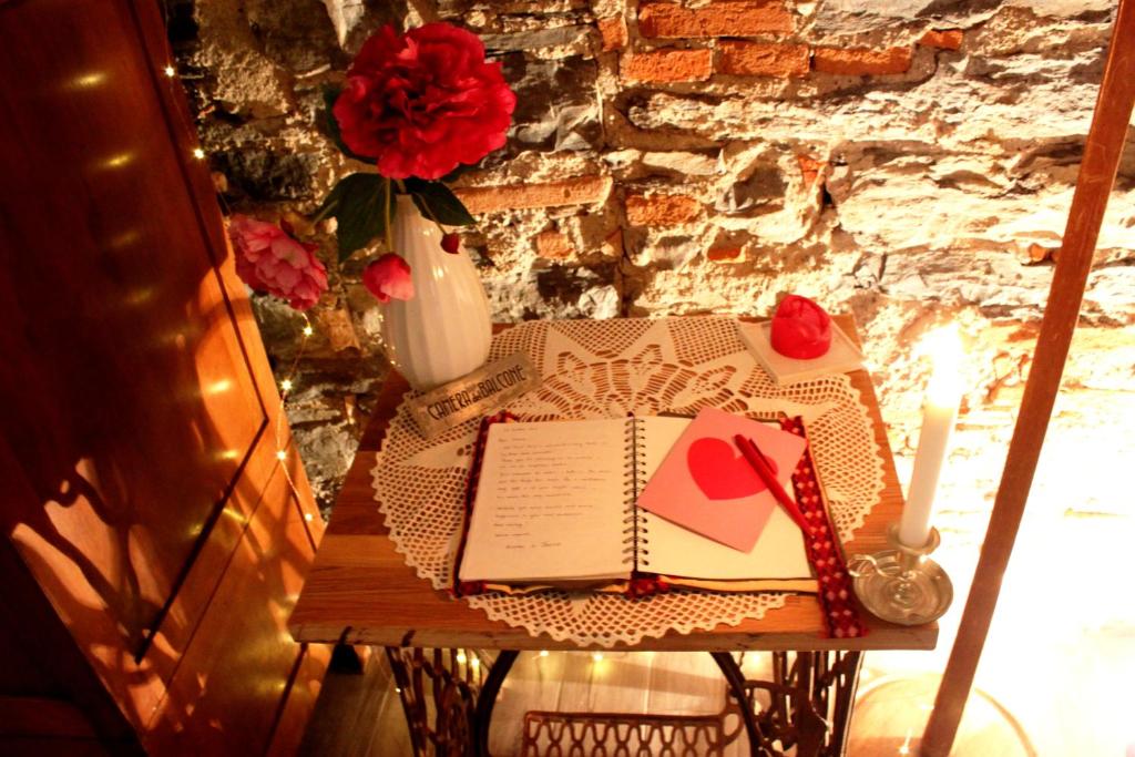 una mesa con un libro y un jarrón con rosas en Le Dame Della Cortesella B&B en Como