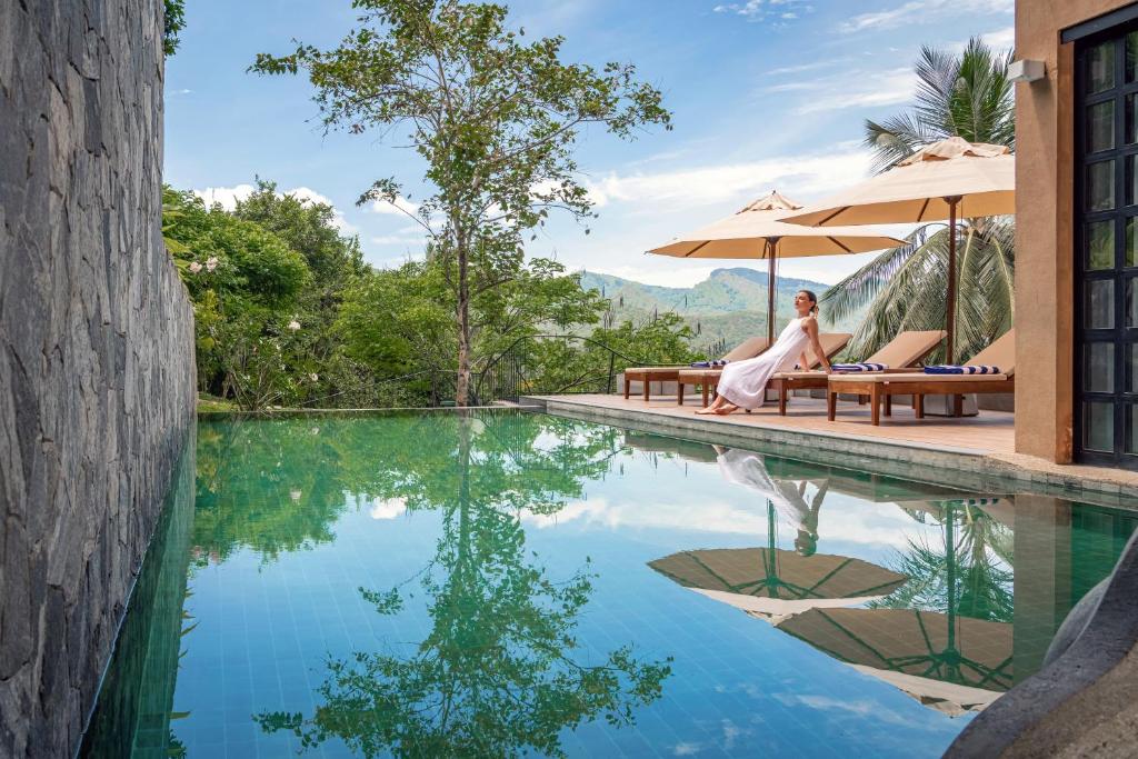 a woman sitting on a bench next to a swimming pool at Ishq Digana in Digana