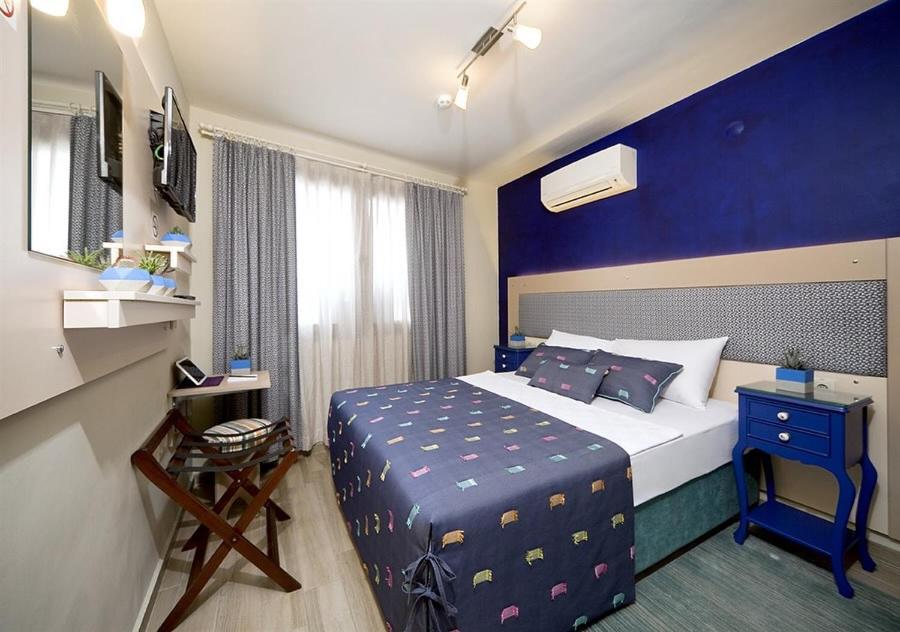 ein Hotelzimmer mit einem Bett und einer blauen Wand in der Unterkunft Dions hotel in Seferihisar