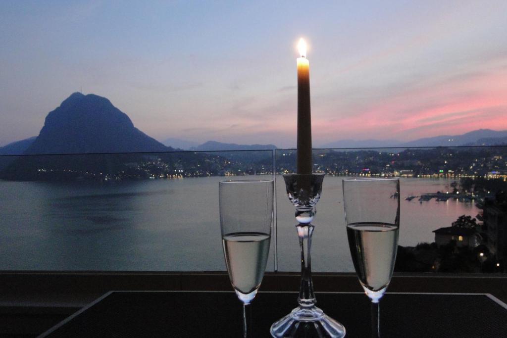 due bicchieri da vino seduti su un tavolo con una candela di Panorama Studio Apartment a Castagnola