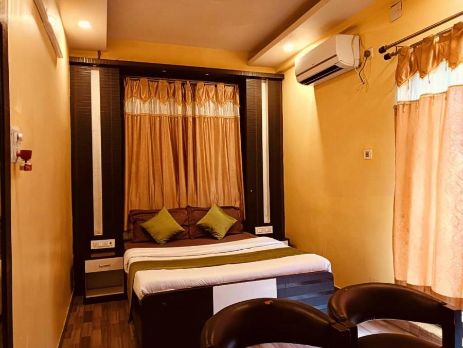 a bedroom with a bed and a window and chairs at royal galaxy hotel in Durgāpur