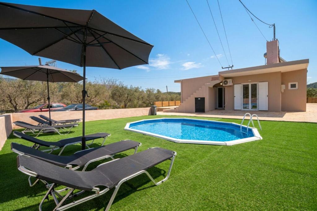 a pool with chairs and umbrellas and a house at Villa Pasiphae by PosarelliVillas in Vamos