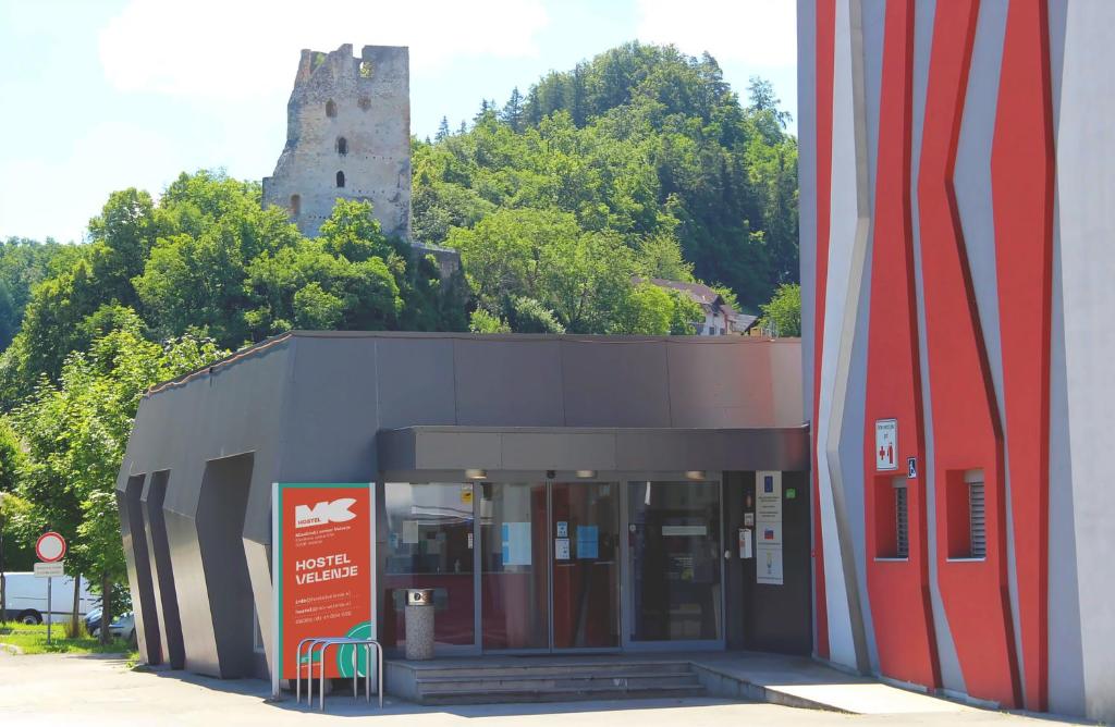 a building with a building with a castle in the background at Hostel Velenje in Velenje