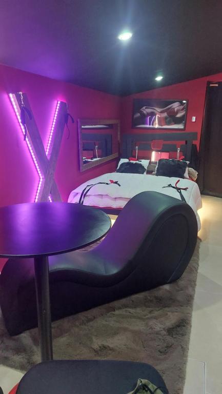 a bedroom with a bed with a table and purple lighting at Love room les pins in Le Muy