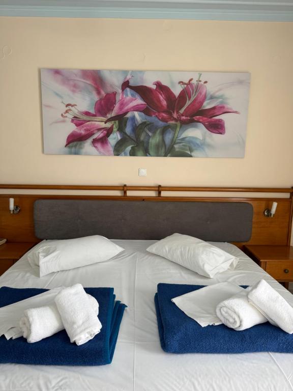 a bed with towels on it with a painting on the wall at Poseidon in Ancient Epidauros
