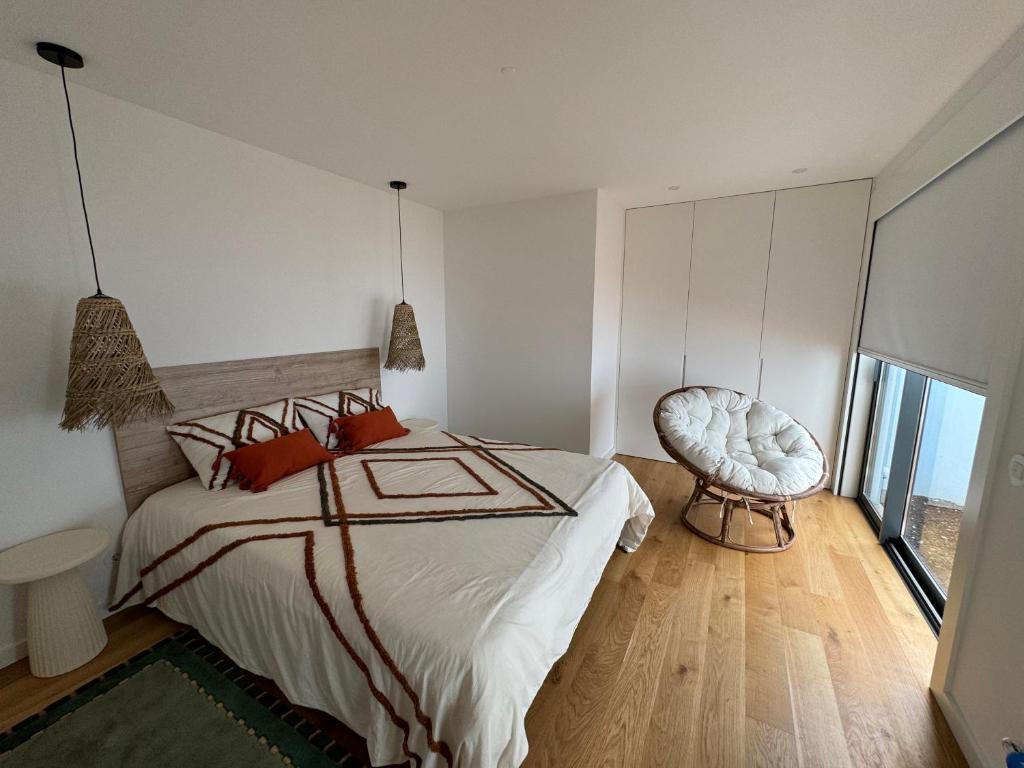 a bedroom with a large bed and a chair at Sea Breeze - Espinho Beach in Espinho